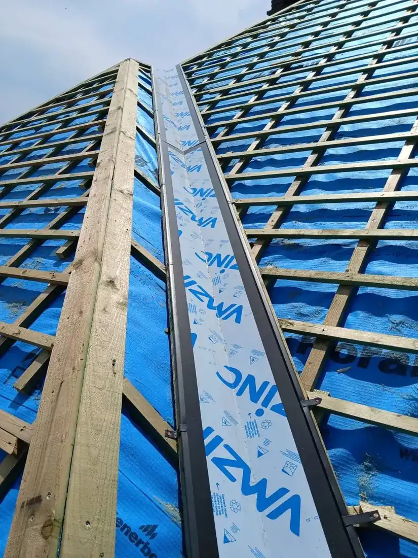 Nieuw lattenwerk en zinken kilgoot tijdens de opbouw van een hellend dak