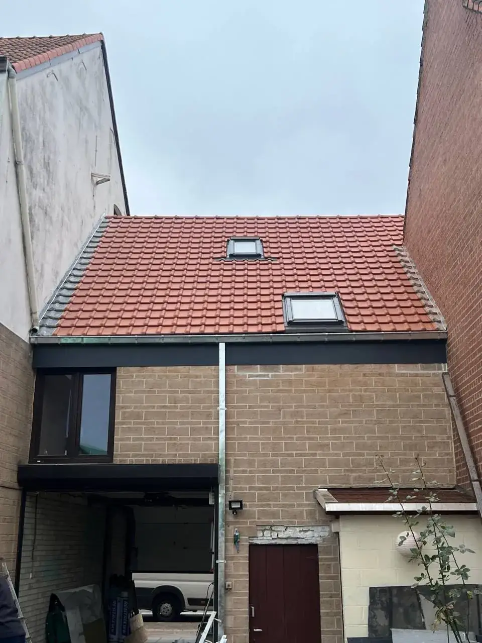 Vernieuwd rood pannendak met twee dakramen op een rijwoning in Korbeek-Dijle