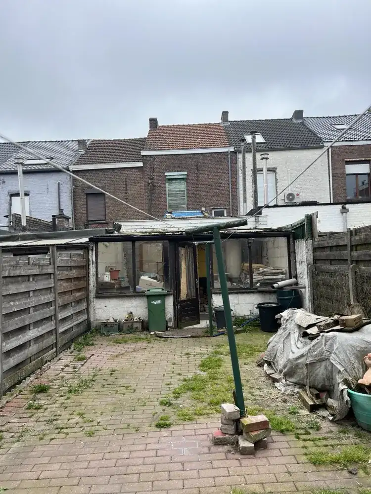 Stadstuin voor de renovatie: verwilderd terras met oude aanbouw